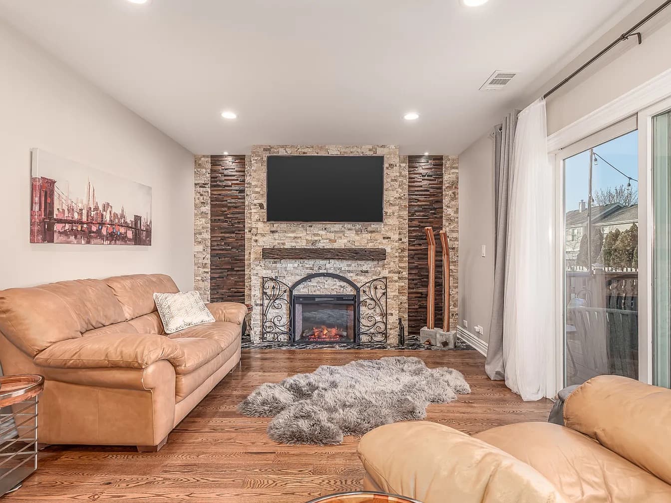 Family room with a floor-to-ceiling stone fireplace wall, leather sofas, and a faux fur rug