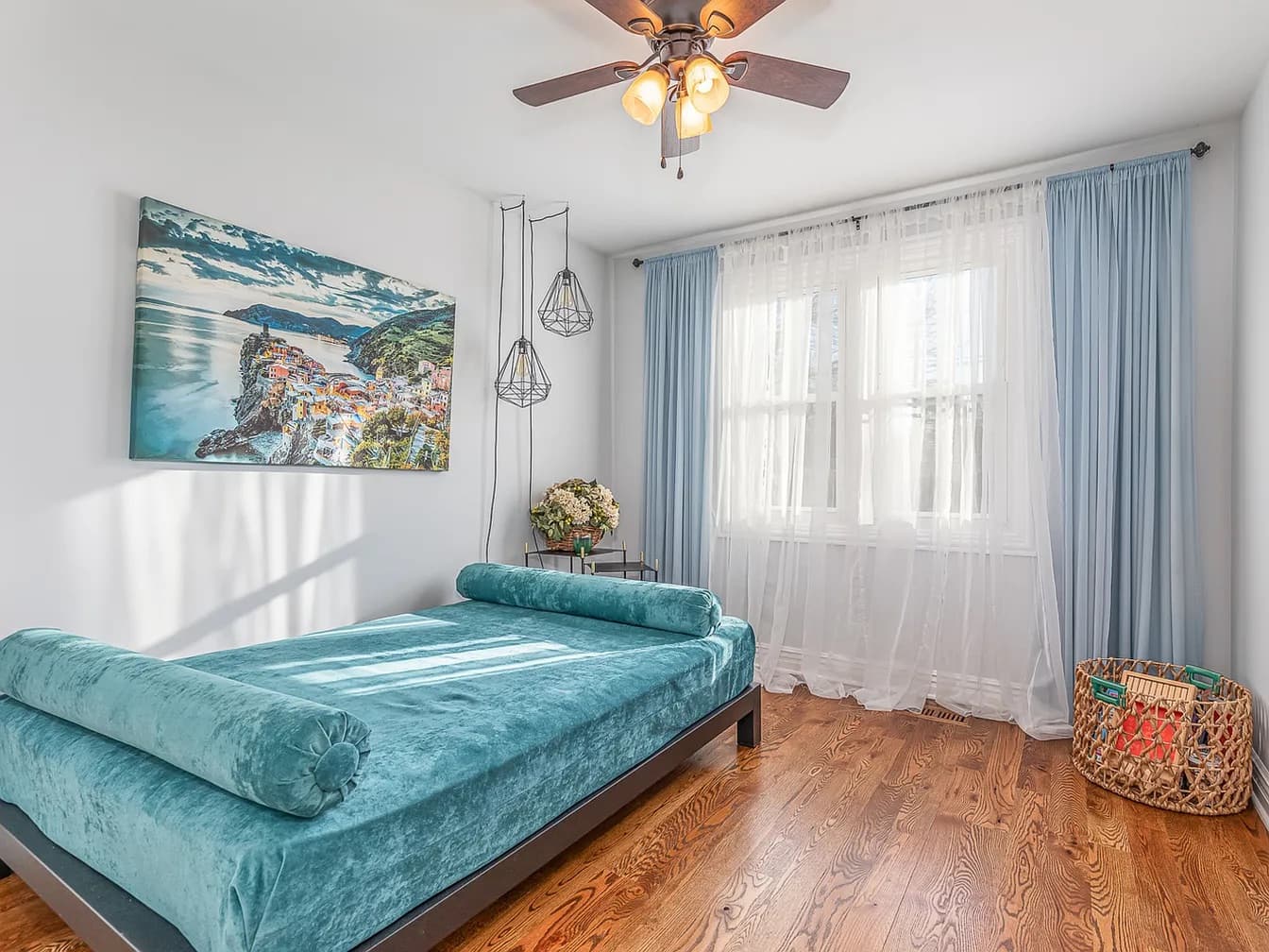 Staged bedroom with teal bedding and sheer drapes
